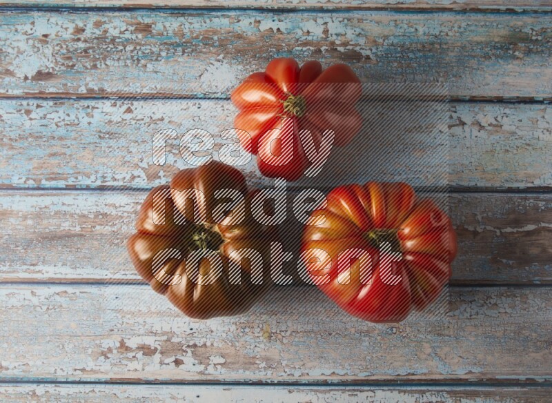 three heirloom tomatoes topview on a textured vinyl background