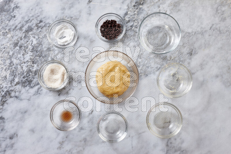 Cookies step by step with its ingredient, flour, butter, brown sugar, egg, vanilla extract, white sugar, chocolate chips and baking soda on grey marble background