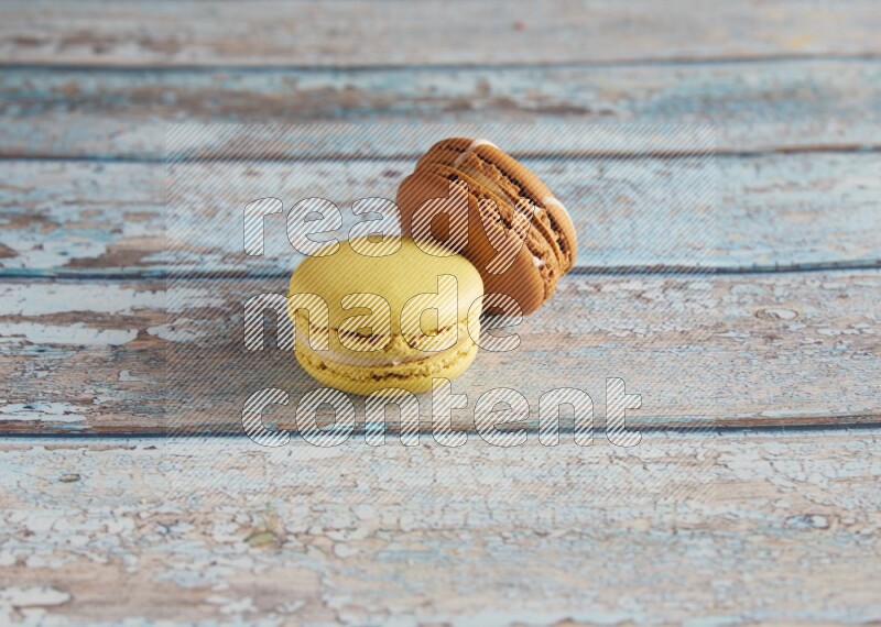 45º Shot of of two assorted Brown Irish Cream, and Yellow Lime macarons on light blue background