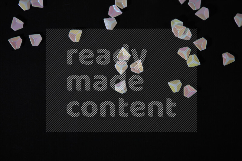Colorful plastic shards for decoration scattered on a black background