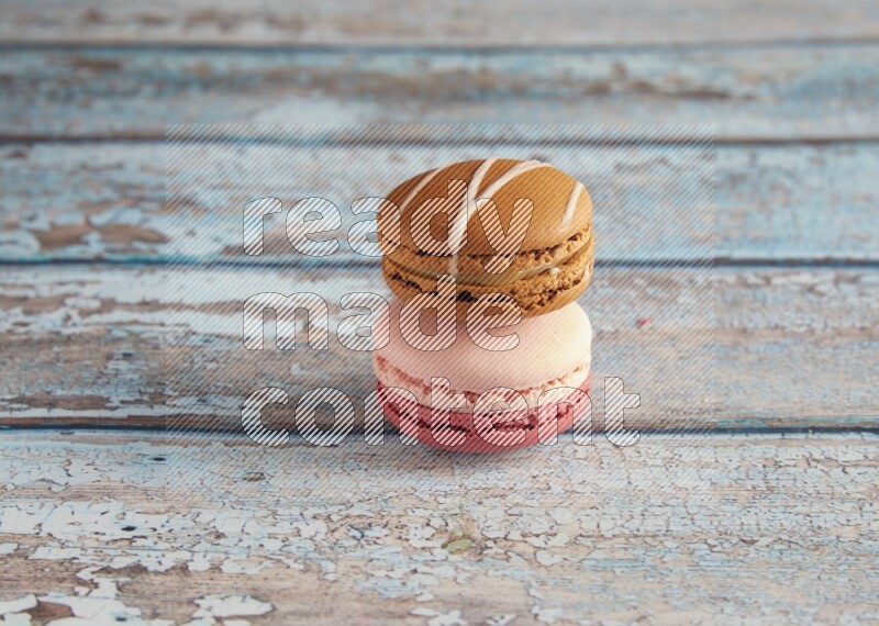 45º Shot of of two assorted Brown Irish Cream, and Pink Litchi Raspberry macarons on light blue background