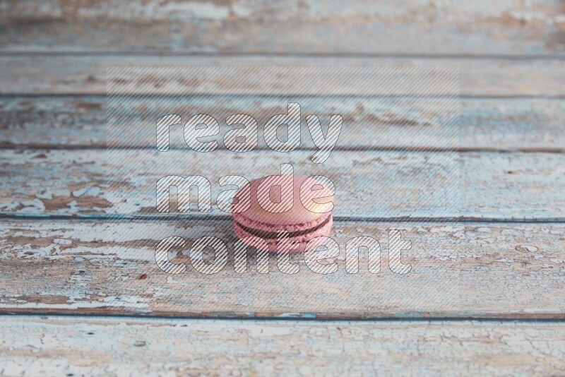 45º Shot of Purple Strawberry macaron on light blue wooden background
