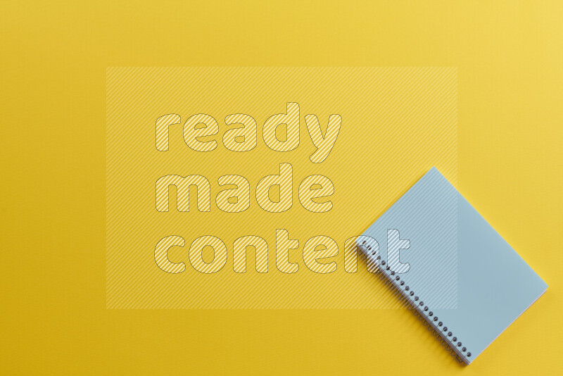 A blue notebook with different school supplies on yellow background