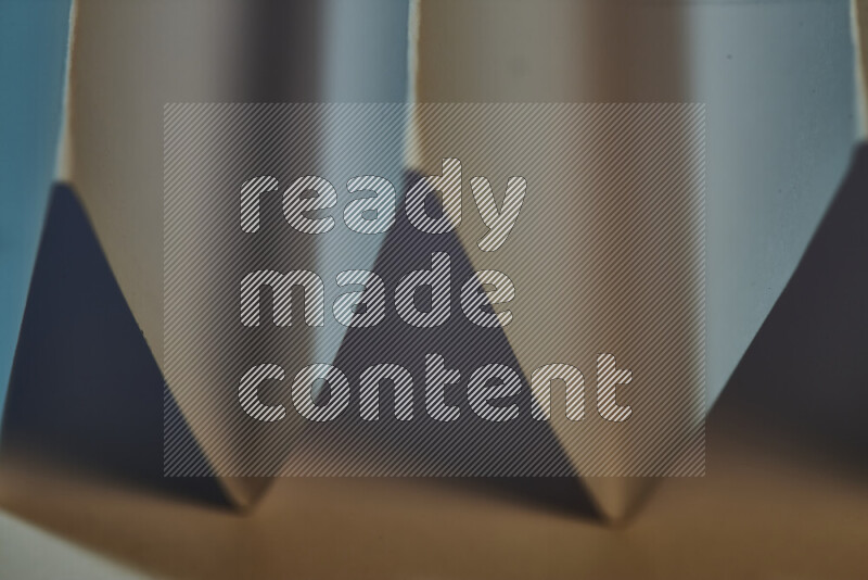 A close-up abstract image showing sharp geometric paper folds in blue gradients and warm tones