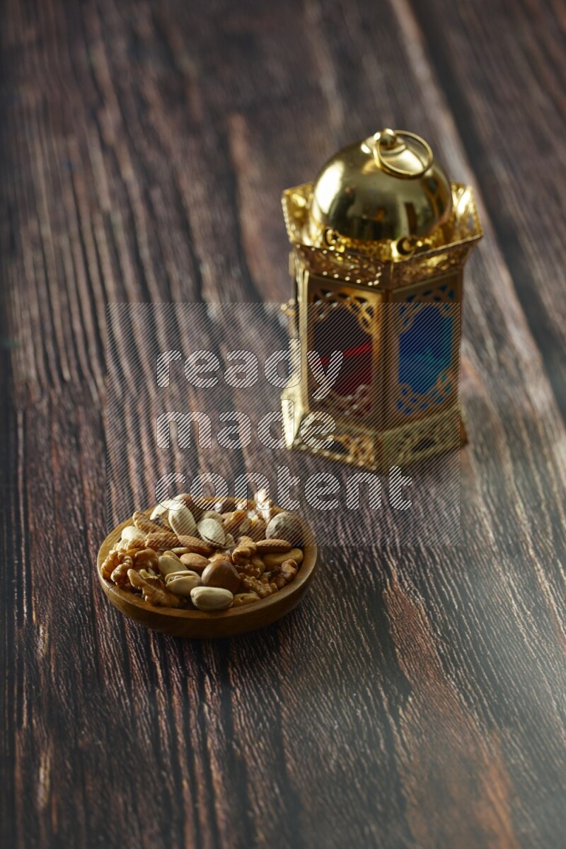 A golden lantern with different drinks, dates, nuts, prayer beads and quran on brown wooden background