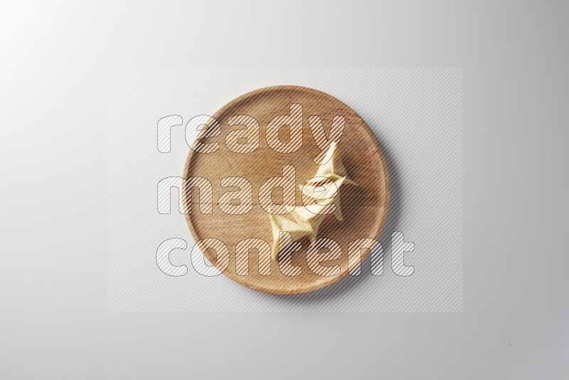 Four Sambosas on a wooden round plate on a white background