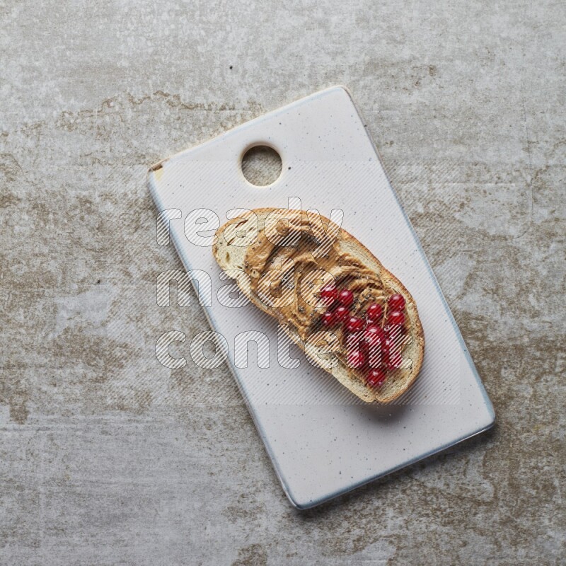 open faced peanut butter sandwich with cranberries and chia seeds grey textured background