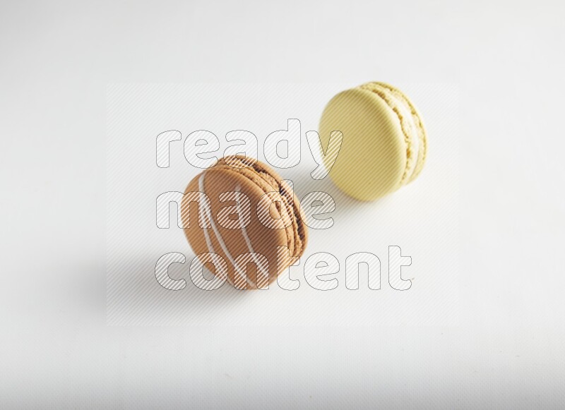 45º Shot of of two assorted Brown Irish Cream, and Yellow Lime macarons on white background