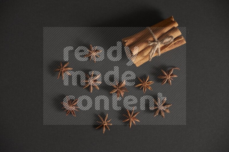 Cinnamon sticks stacked and bounded and star anise on black background