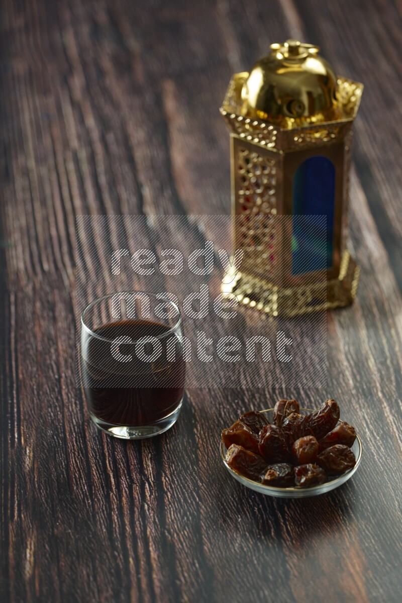 A golden lantern with different drinks, dates, nuts, prayer beads and quran on brown wooden background
