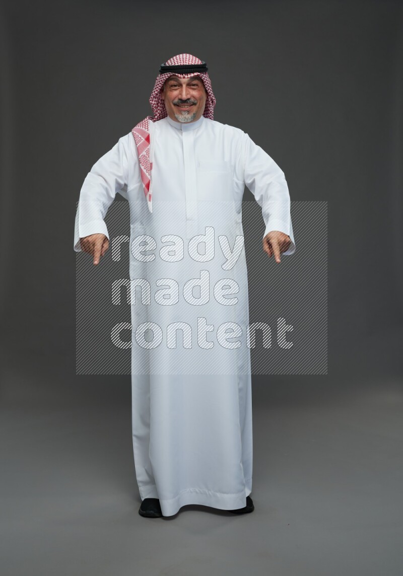 Saudi man with shomag Standing Interacting with the camera on gray background