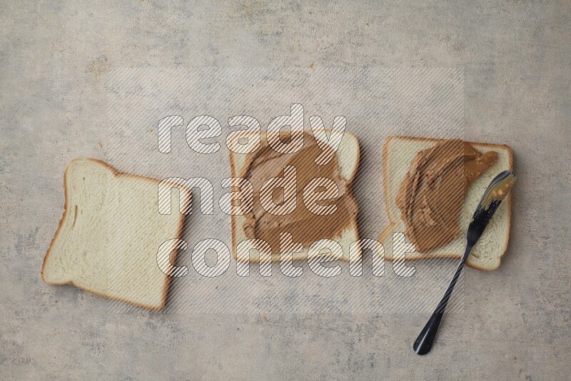 Creamy peanut butter on white toast and white toast slices on a light blue textured background