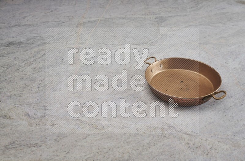 A small copper pan on grey marble background