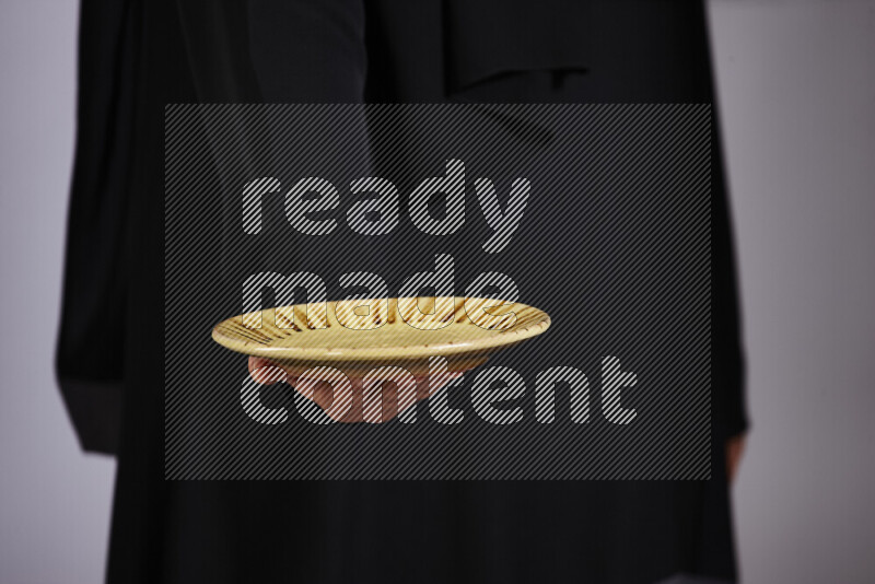 A woman in black abaya holding different pottery essentials in different positions