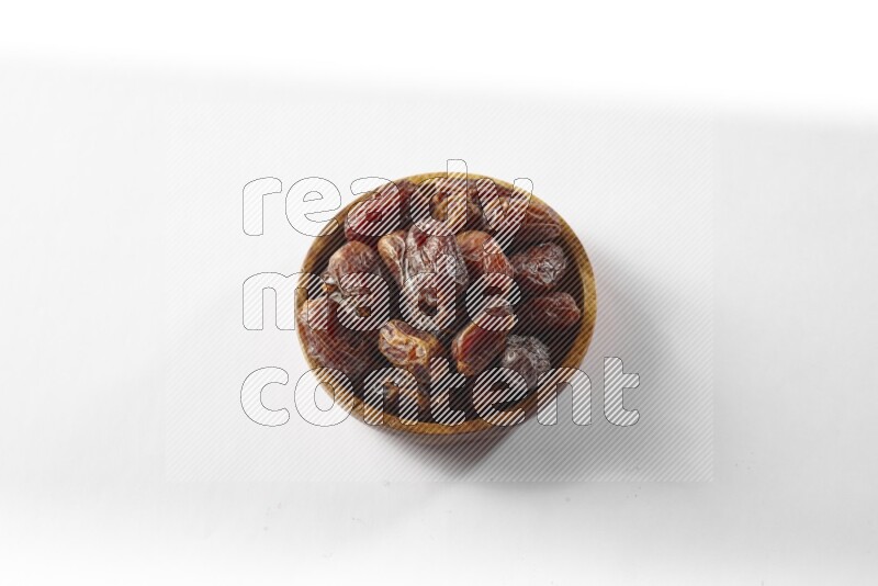 Dates in a wooden bowl on white background