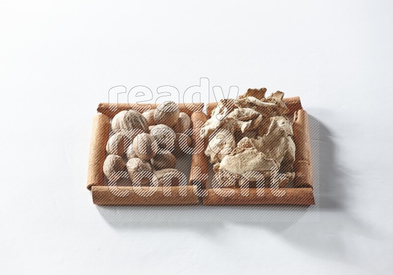 2 squares of cinnamon sticks full of dried ginger and nutmegs on white flooring