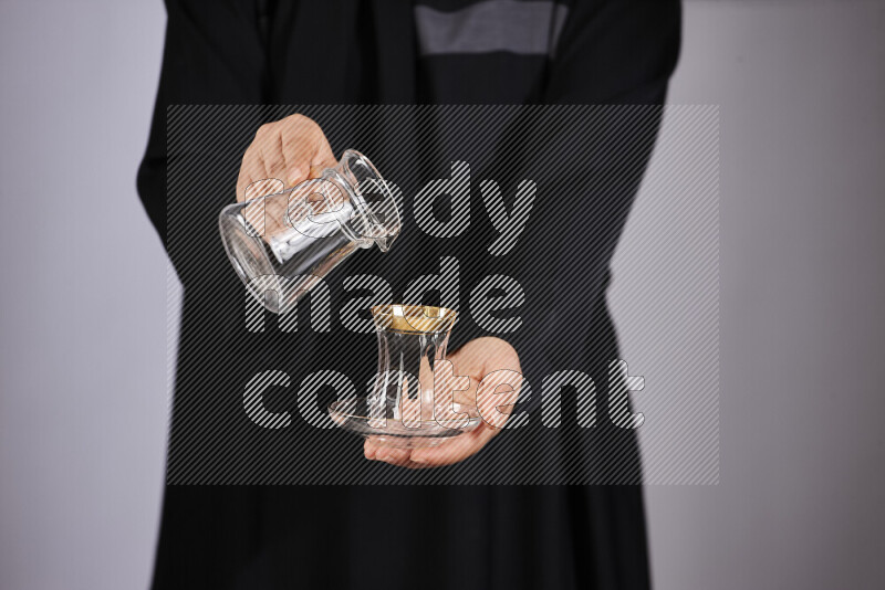 A woman in black abaya holding different glassware in different positions