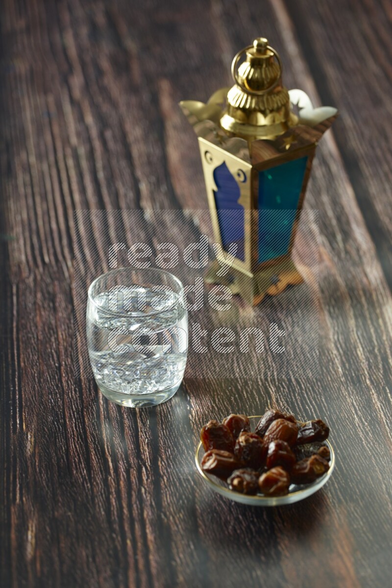 A golden lantern with different drinks, dates, nuts, prayer beads and quran on brown wooden background