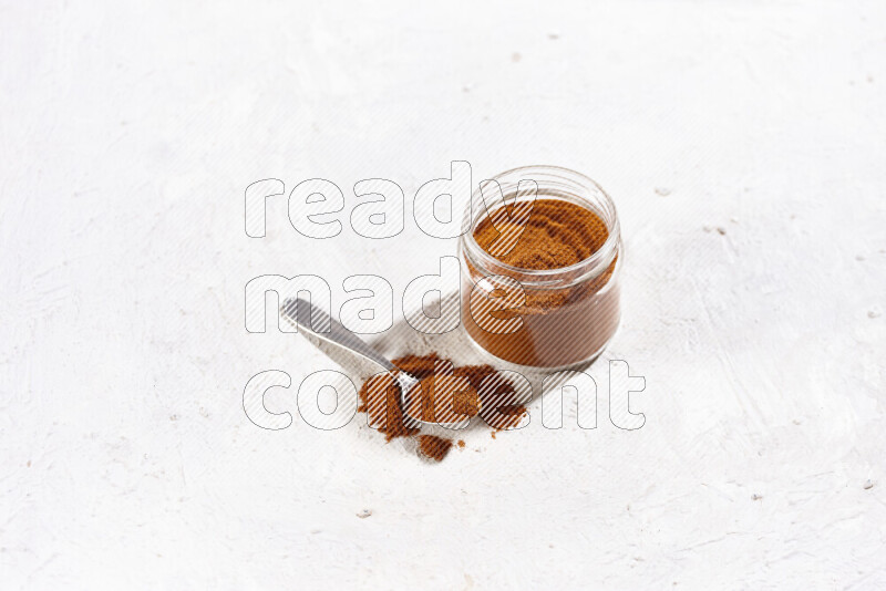 A glass jar full of ground paprika powder on white background