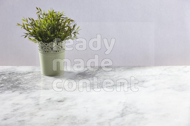 Artificial plant in green decorative pot on grey marble background