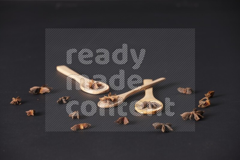 Star Anise in wooden spoons on black flooring