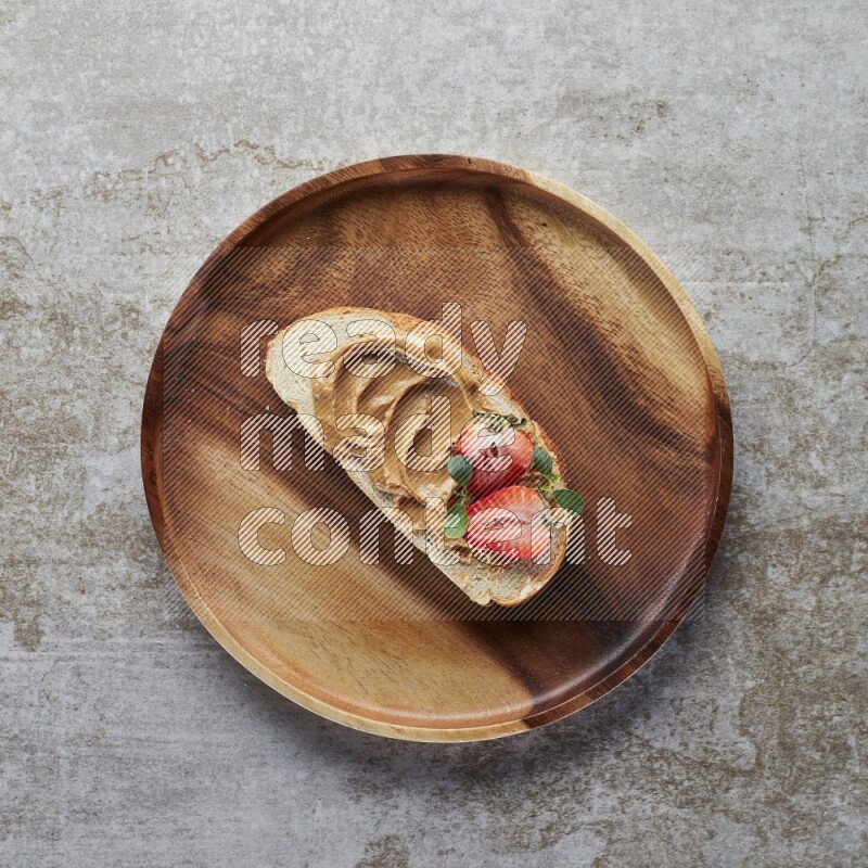 open faced peanut butter sandwich with strawberries on a grey textured background