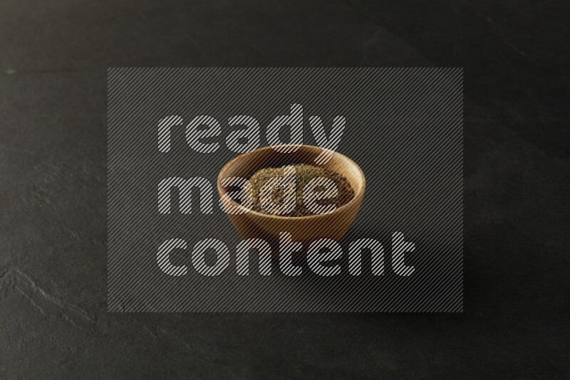 wooden round sauce bowl filled with herbs on grey textured countertop