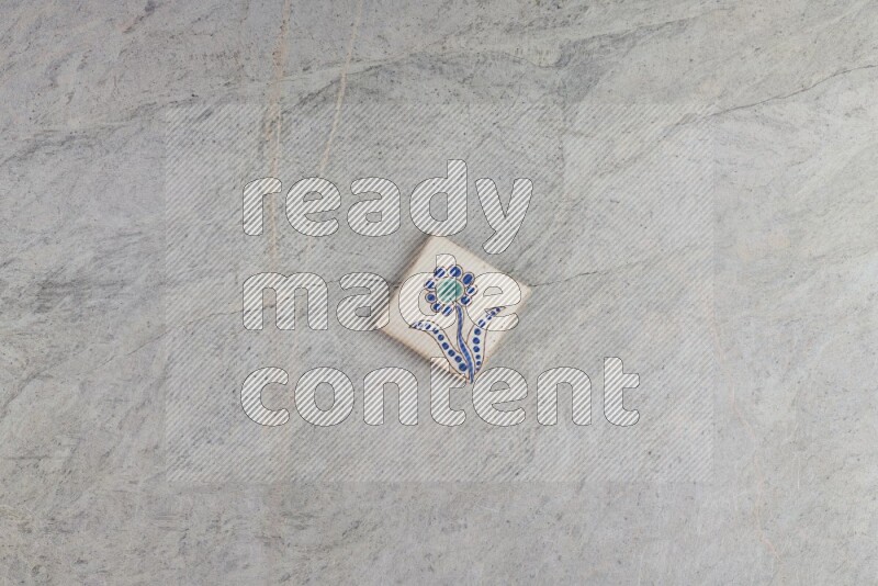 A decorative pottery coaster on grey marble background