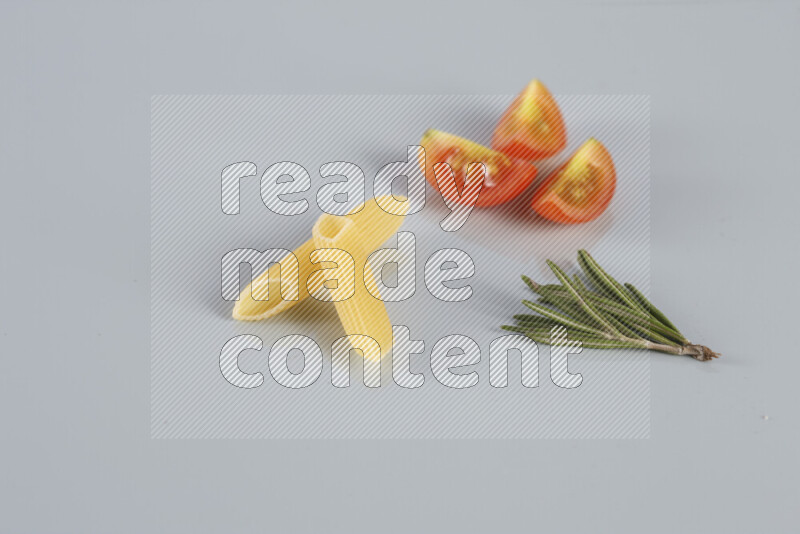 Raw pasta with different ingredients such as cherry tomatoes, garlic, onions, red chilis, black pepper, white pepper, bay laurel leaves, rosemary, cardamom and mushrooms on light blue background