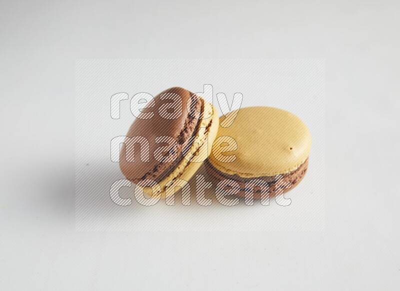 45º Shot of two Yellow and Brown Chai Latte macarons on white background