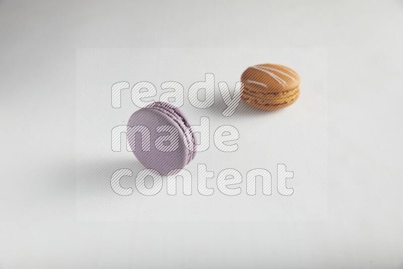 45º Shot of of two assorted Brown Irish Cream, and Purple Blueberry macarons on white background