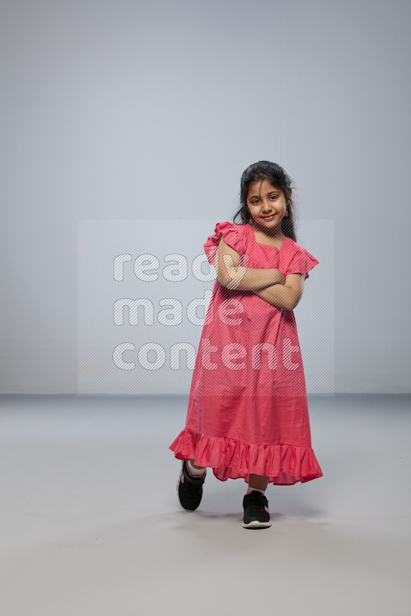 A girl standing interacting with the camera on gray background
