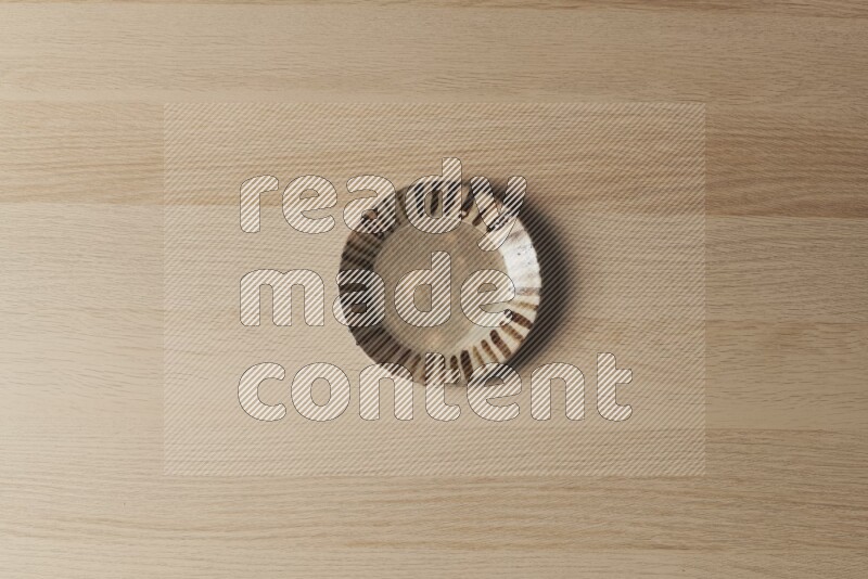 A multicolored pottery plate on light wooden background