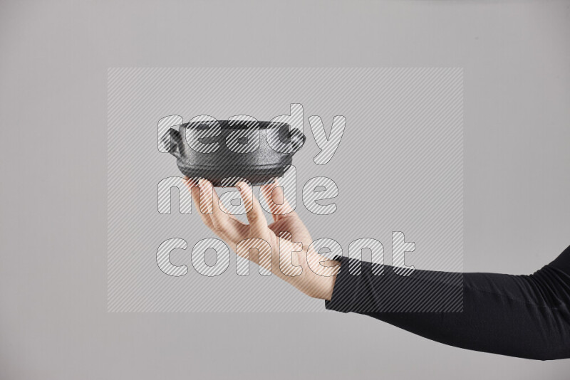 A woman in black abaya holding different pottery essentials in different positions
