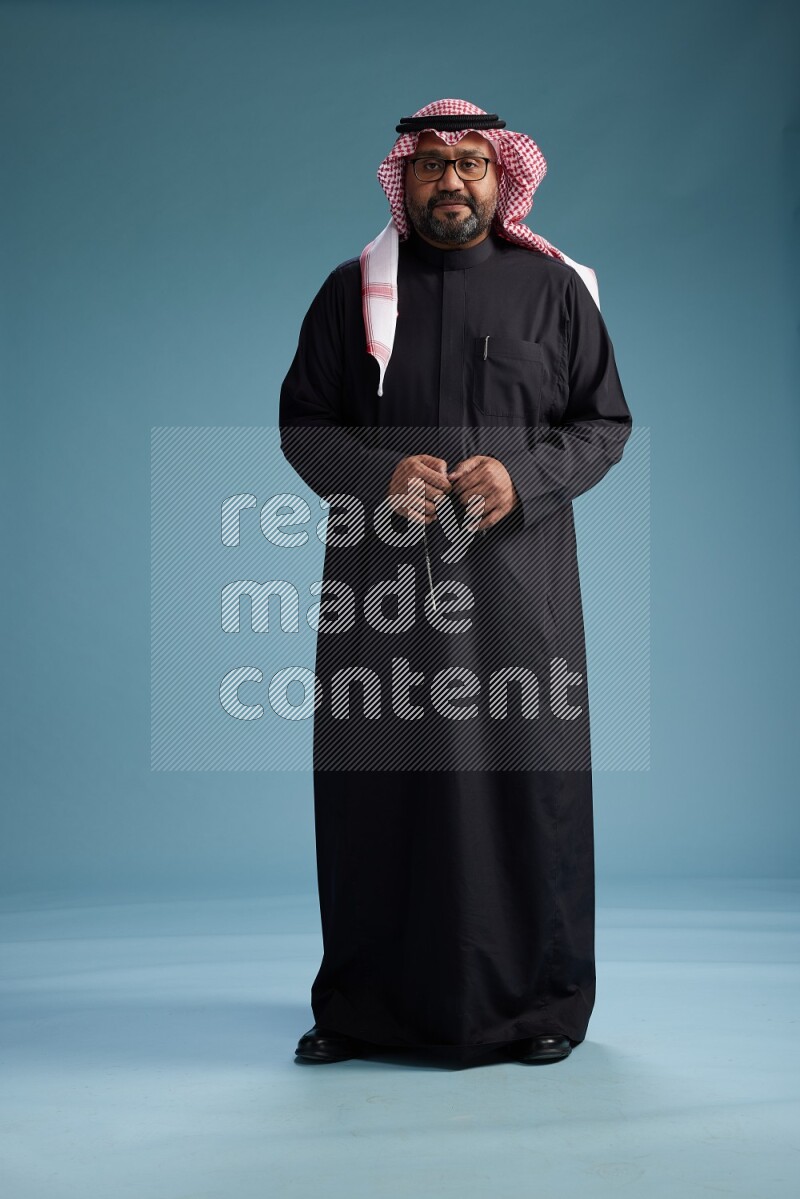 Saudi Man with shimag Standing Interacting with the camera on blue background
