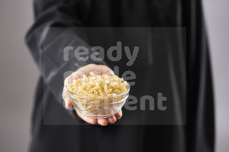 Woman in abaya holding different kinds of pasta in different positions