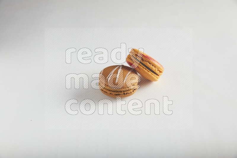 45º Shot of of two assorted Brown Irish Cream, and Orange Exotic macarons on white background