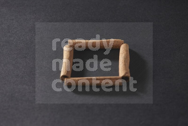 A single square of cinnamon sticks on black flooring