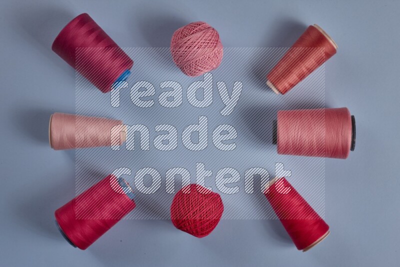 A pink collection of sewing and tailoring tools arranged on a blue background