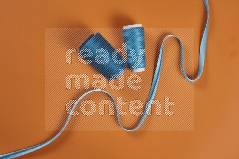 A blue collection of sewing and tailoring tools arranged on a orange background
