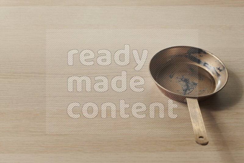 A small copper pan on light wooden background