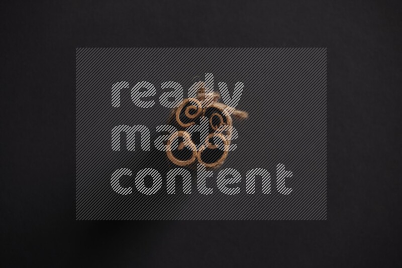 4 Cinnamon sticks stacked and bounded on black flooring