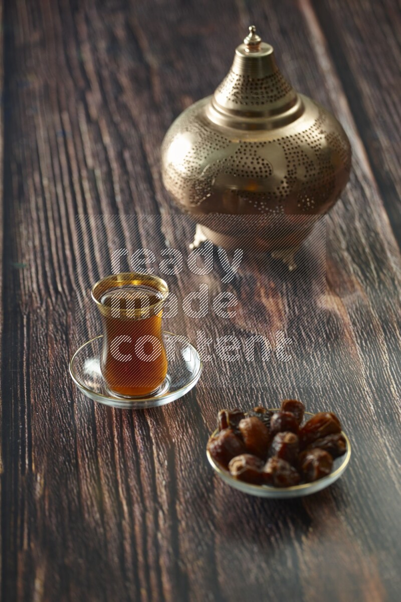 A golden lantern with different drinks, dates, nuts, prayer beads and quran on brown wooden background