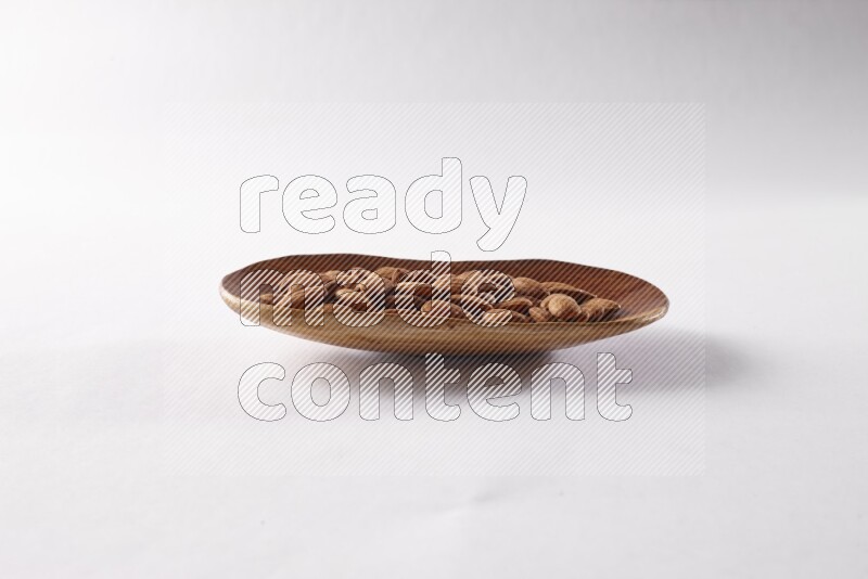 Almonds in a wooden plate on white background