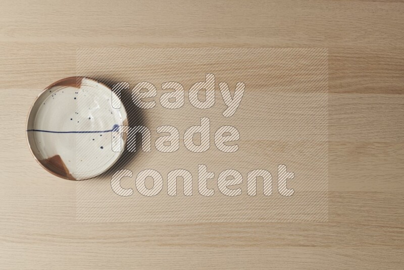 A multicolored pottery plate on light wooden background