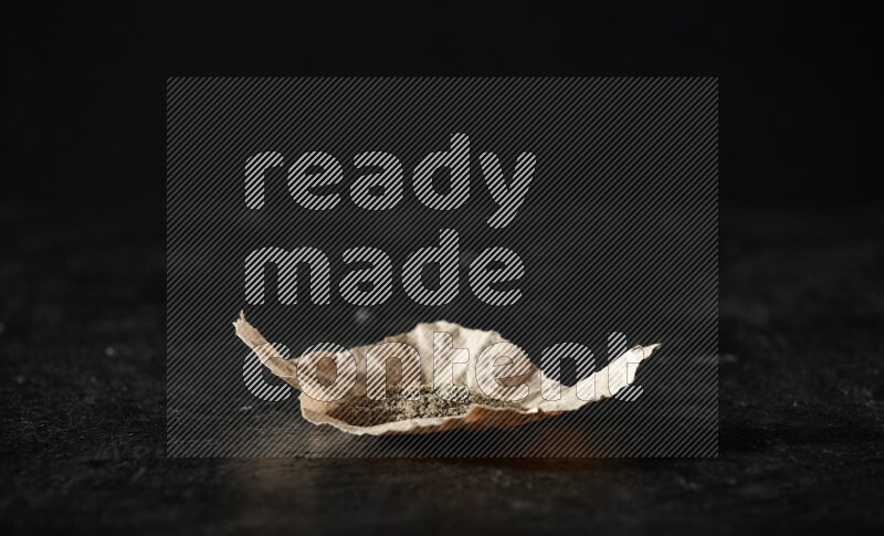 بودرة الهيل في قطعة من الورق على خلفية سوداء