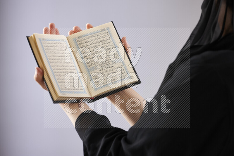 امرأة تحمل بيديها مصحف القرآن في أوضاع متعددة