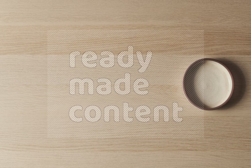 A beige pottery oven bowl on light wooden background
