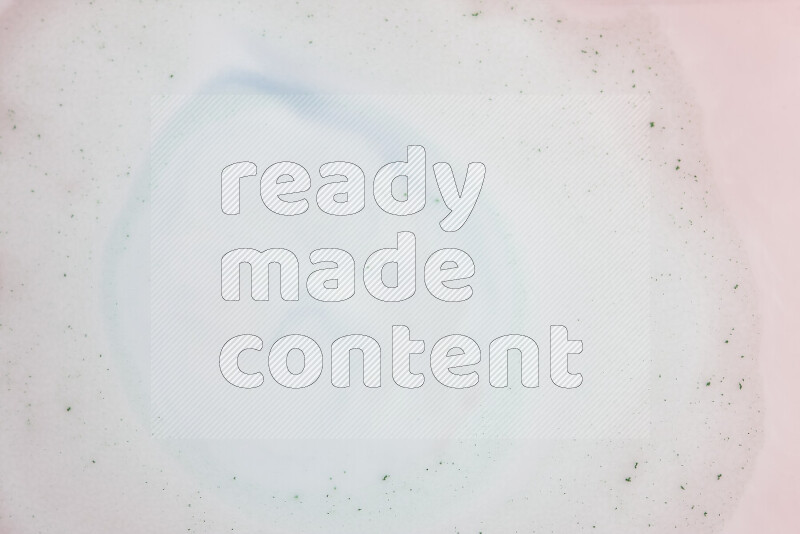 The image presents a swirl of pastel pink and pale blue with green droplets on white background