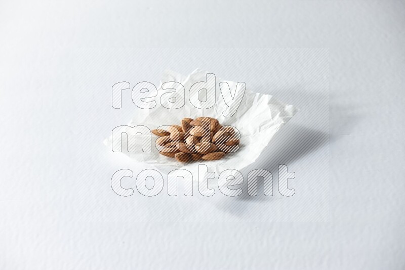 Peeled almonds on a crumpled piece of paper on a white background in different angles